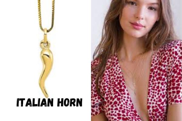 Gold Italian Horn necklace on a person wearing a red and white patterned top.