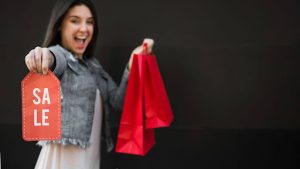 A woman showing a red color sale badge and 2 red color shopping bags like she is ready for Labor Day sale.