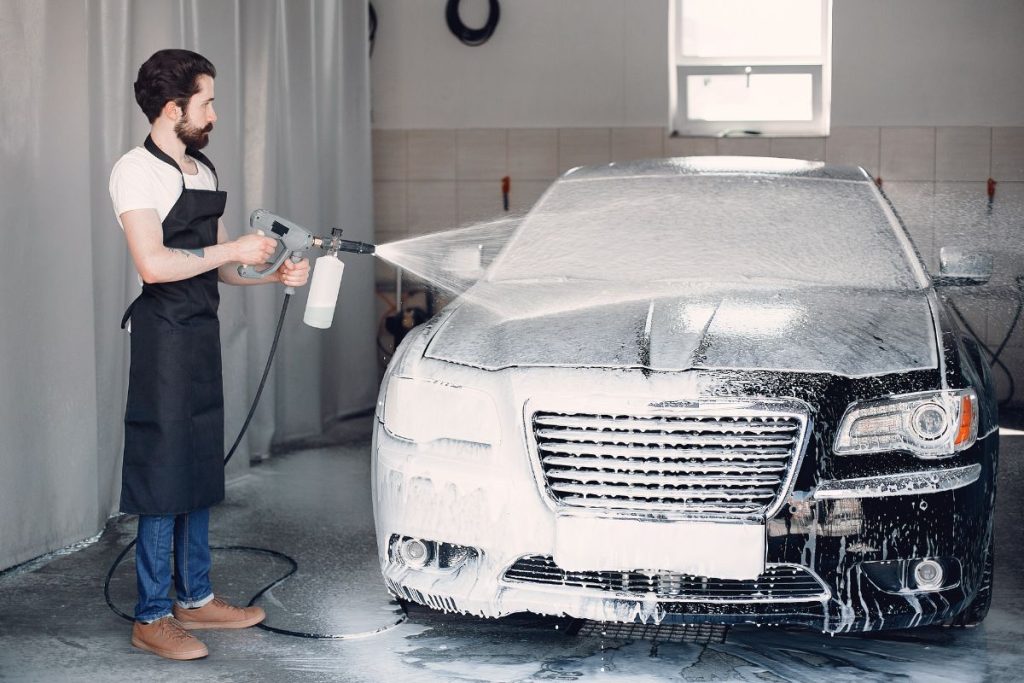 Car being cleaned at a touchless car wash with high-pressure water jets