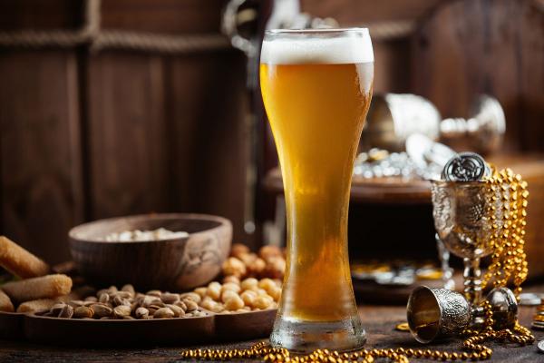 A bottle of malt liquor with a distinct label and a frothy glass of the beverage beside it, placed on a wooden table.